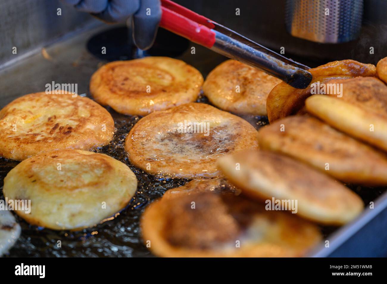 Hotteok, koreanischer, mit Sirup gefüllter Pfannkuchen : fermentierter Mehlteig in Form von Kugeln, gefüllt mit einem Löffel braunem Zucker und in der Pfanne gebraten in einem vorgewärmten Pa Stockfoto