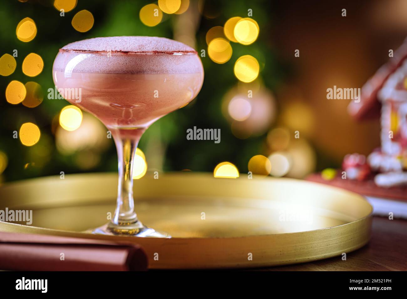 Cocktailgetränk mit Espresso-Kaffee in einem Coupé-Glas auf einem goldenen Tablett. Weihnachtsdekoration mit Lichtern im Hintergrund. Silvesterparty-Atmosphäre. Stockfoto