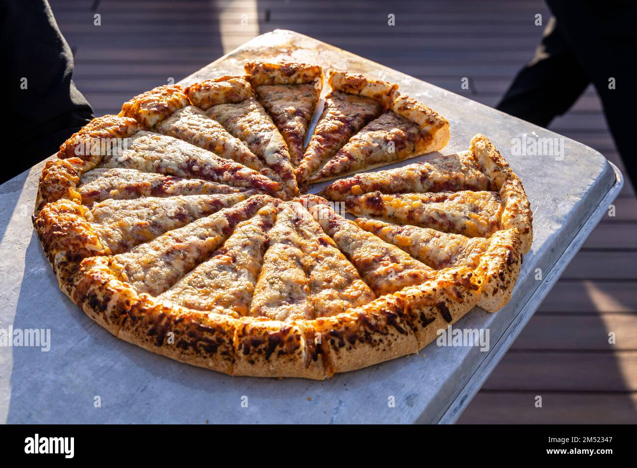 Ein Stockbild einer großen Pizza in Scheiben, serviert in einem Büfett im Freien. Stockfoto
