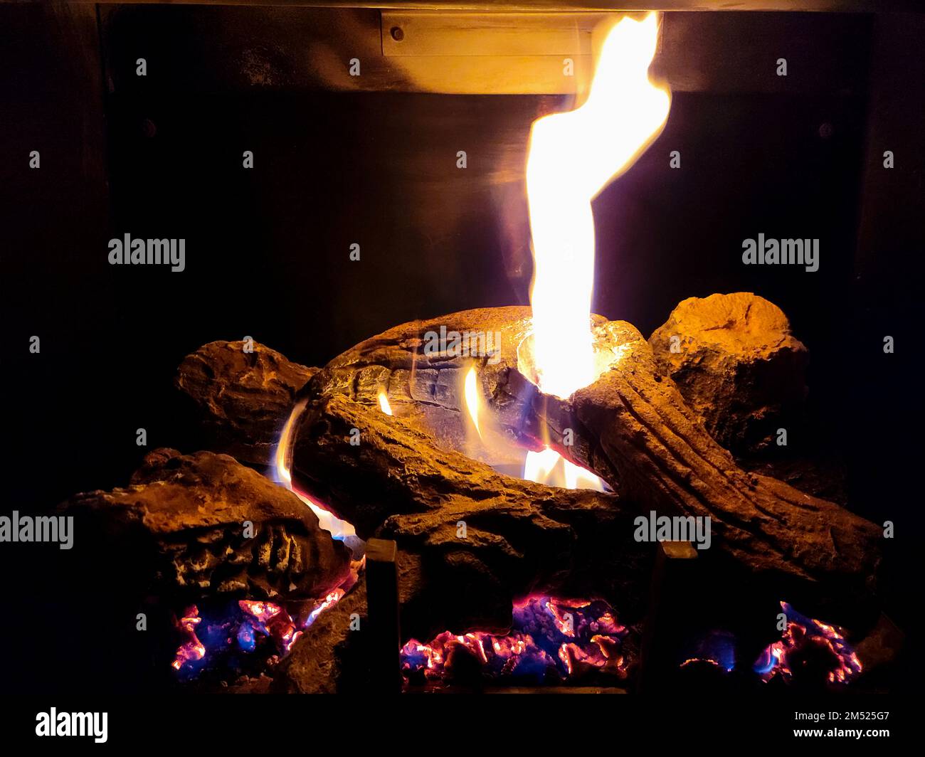 Glühende Baumstämme im Kamin mit Flammen und Glut Stockfoto