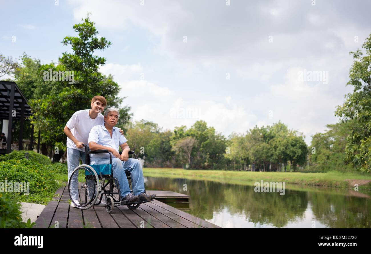 Asiatische sorgfältige Pflegekraft oder Krankenschwester halten die Hand des Patienten und ermutigen den Patienten in einem Rollstuhl. Konzept der glücklichen Ruhestand mit Pflege aus einer caregiv Stockfoto