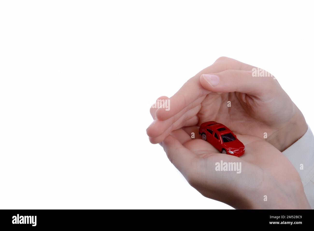 Des Kindes Hand hält ein rotes Auto auf weißem Hintergrund Stockfoto