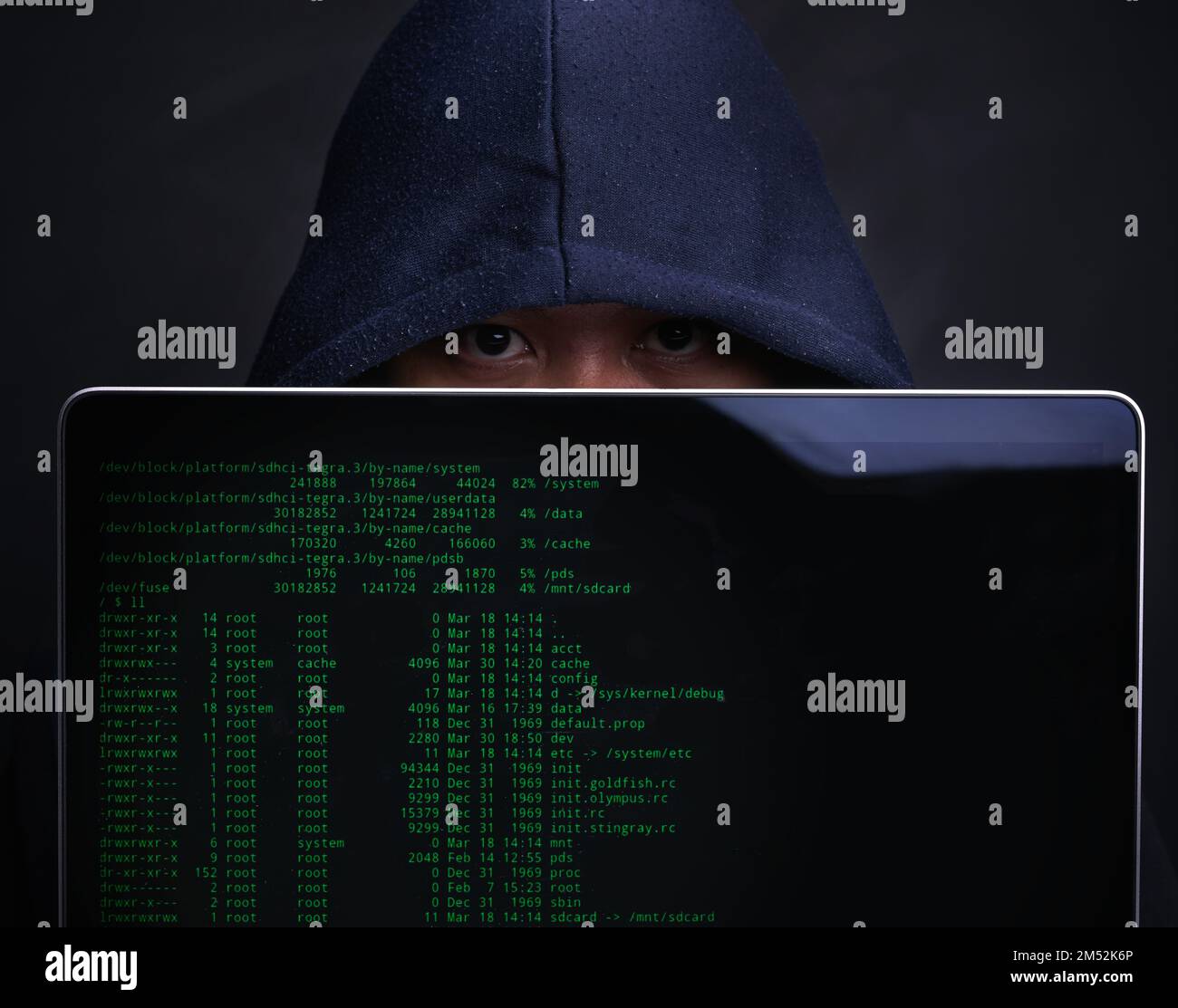 Jemand hat jeden deiner Schritte online im Auge behalten. Porträt eines Hackers, der einen Laptop vor einem dunklen Hintergrund hält. Stockfoto