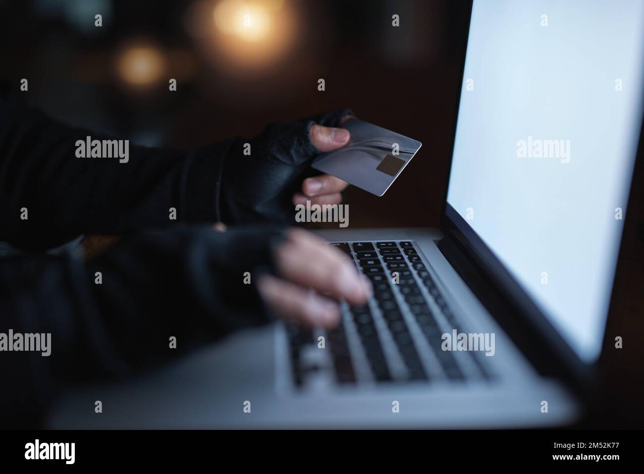 Hacker haben keine Angst davor, sich an Ihren Besitztümern zu bedienen. Ein nicht wiedererkennbarer Hacker, der einen Laptop benutzt, um sich in ein Kreditkonto zu hacken. Stockfoto