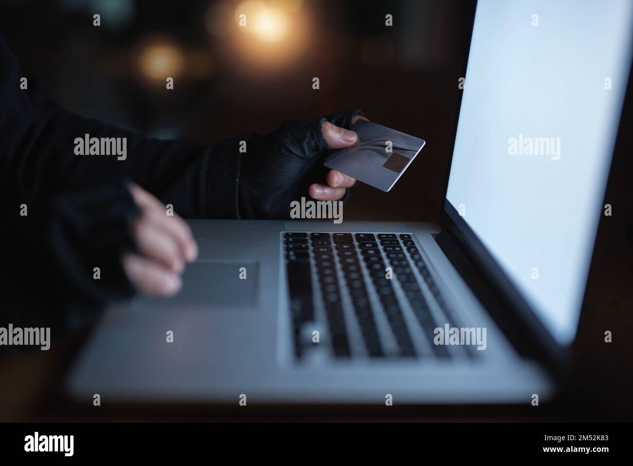 Schützen Sie sich davor, das nächste Opfer von Betrug zu werden. Ein nicht wiedererkennbarer Hacker, der einen Laptop benutzt, um sich in ein Kreditkonto zu hacken. Stockfoto
