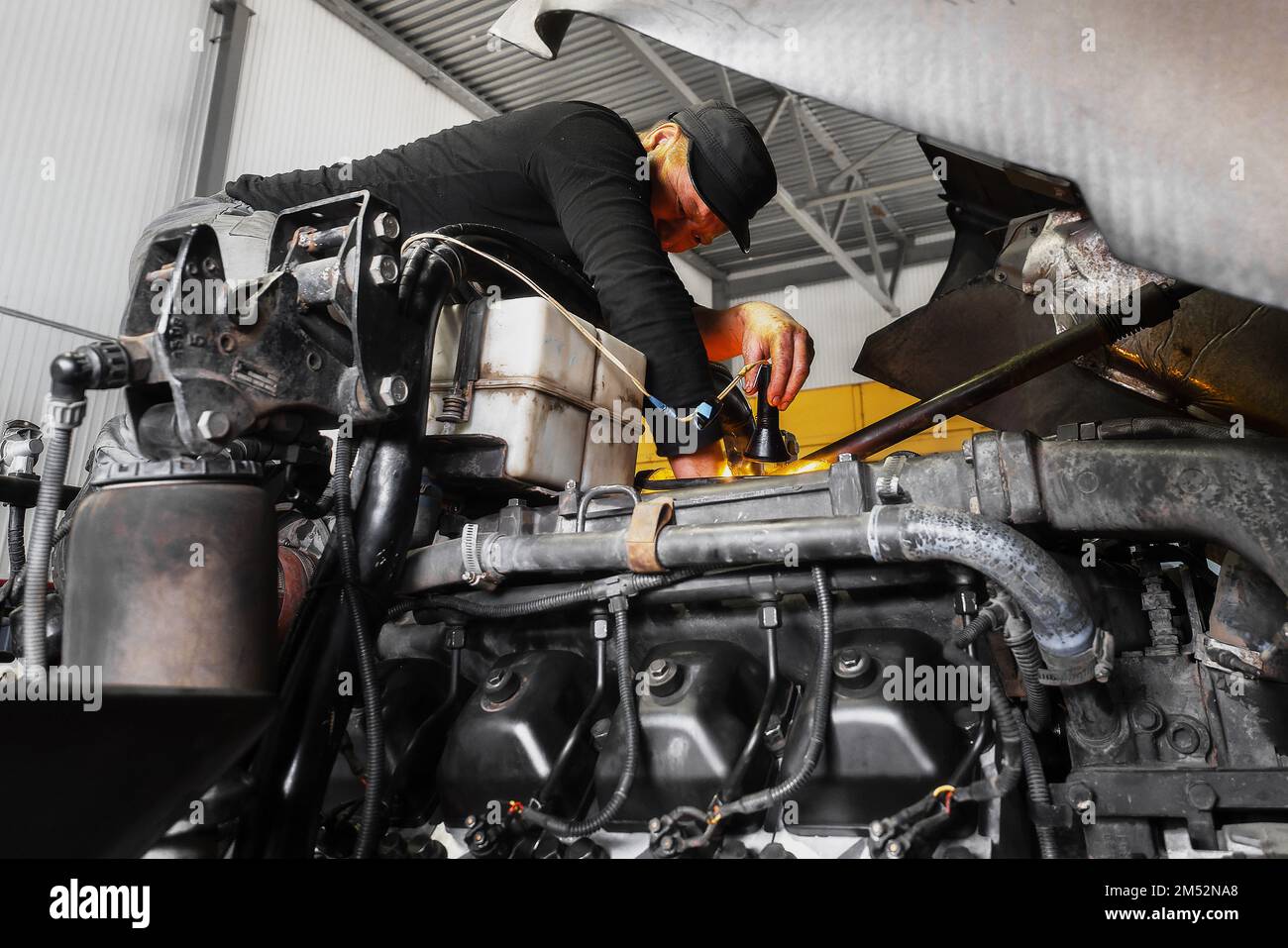 Automechaniker repariert großen Lkw oder Traktor in der Werkstatt. Professioneller Mechaniker repariert Lkw-Motor. Aufrichtiger Arbeiter. Stockfoto