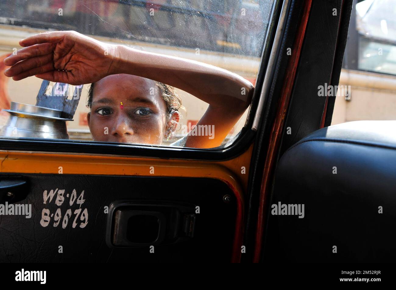 Ein junger Bettler klopfen am Fenster und Taxis auf einer belebten Straße in Kalkutta. Stockfoto