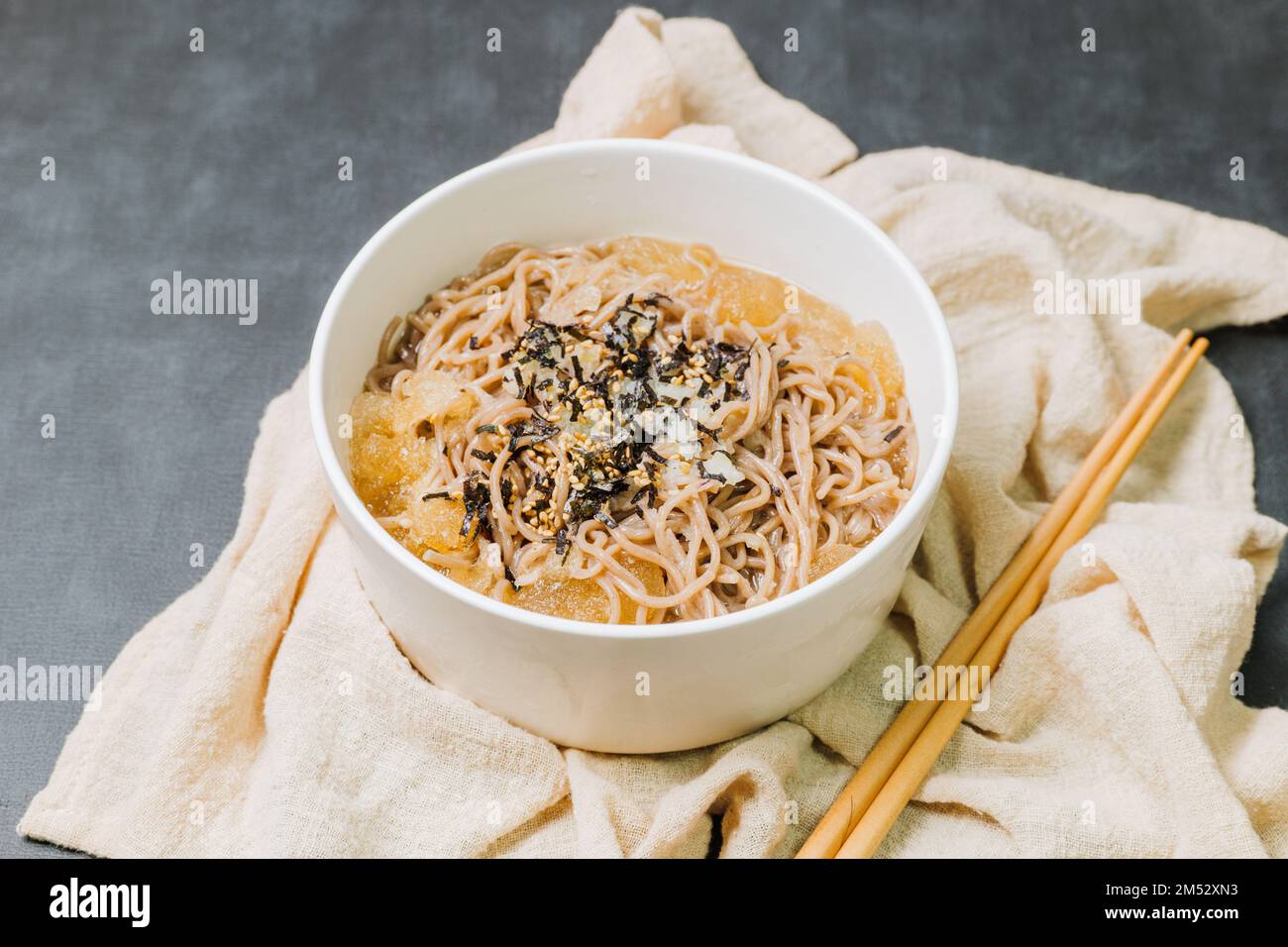 Koreanische Küche Naengmemilguksu, eine winterliche Delikatesse, wird dieses Buchweizen-Nudelgericht in einer kalten Hühnchen- oder Rinderbrühe serviert und mit einer kalten Scheibe garniert Stockfoto