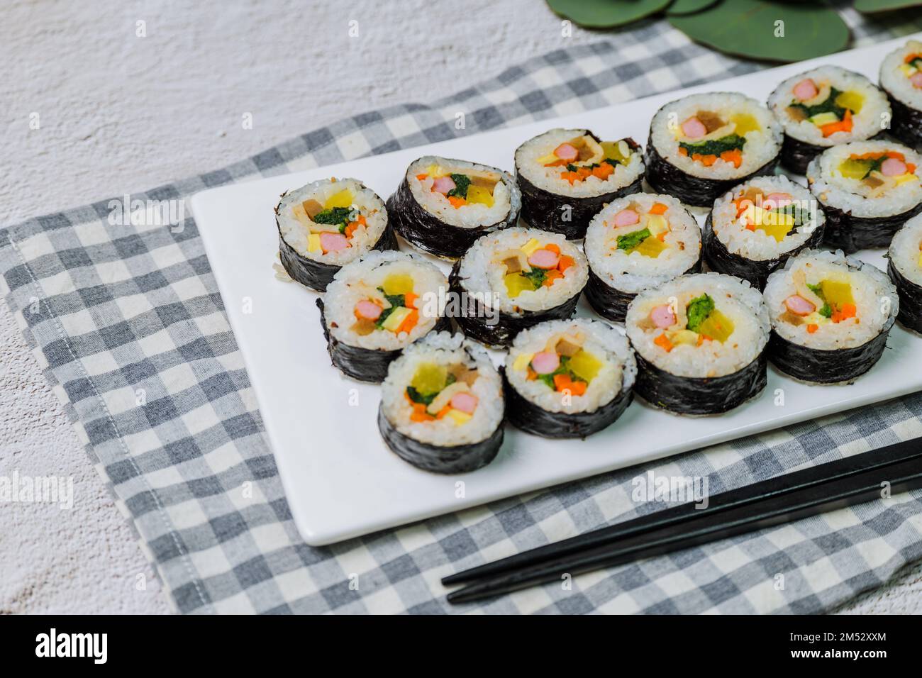 Reis mit Salz und Sesamöl gewürzt und in ein Blatt gerösteten gim (getrockneter Lava) mit Spinat, Karotten und eingelegtem weißem Rettich gerollt. Der lange Stockfoto