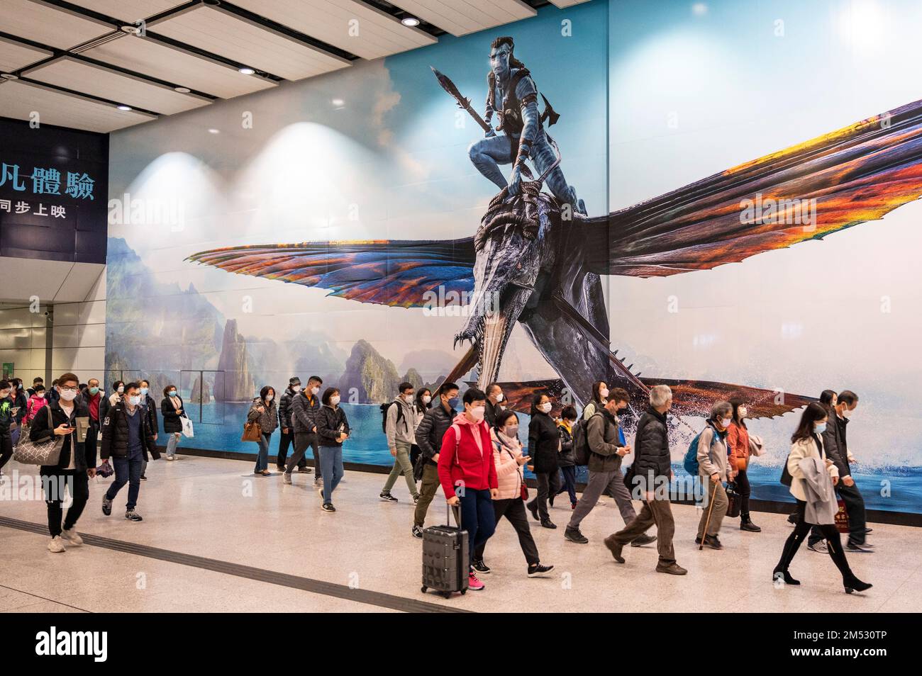 Hongkong, China. 24. Dezember 2022. Pendler gehen an einem großen Werbebanner vorbei, auf dem der Film Avatar: The Way of Water (Avatar 2) vorgestellt wird, der von Lightstorm Entertainment produziert und von 20. Century Studios in Hongkong vertrieben wird. Kredit: SOPA Images Limited/Alamy Live News Stockfoto