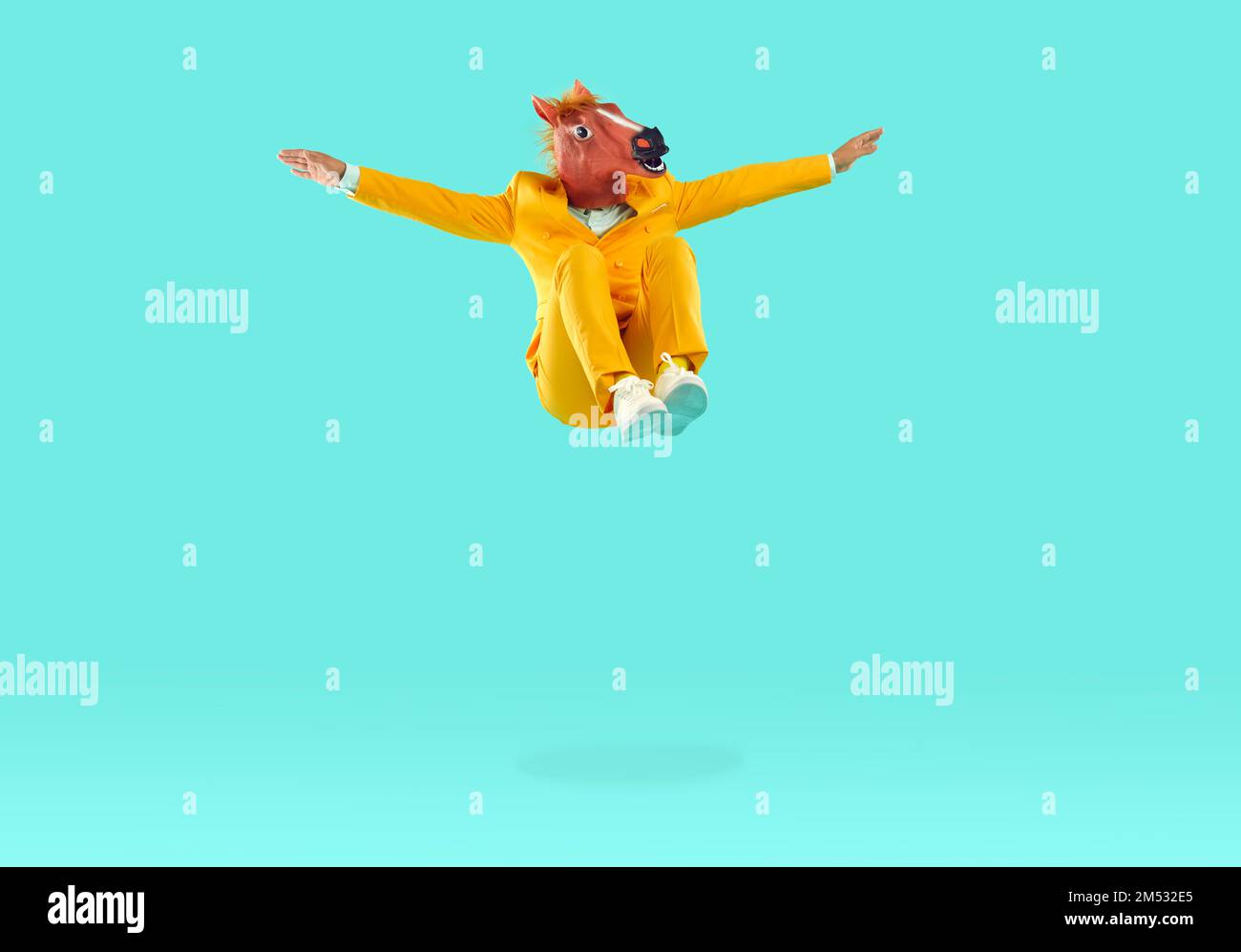 Mann mit Dinosaurierkopf, der auf gelbem Hintergrund in die Luft springt Stockfoto