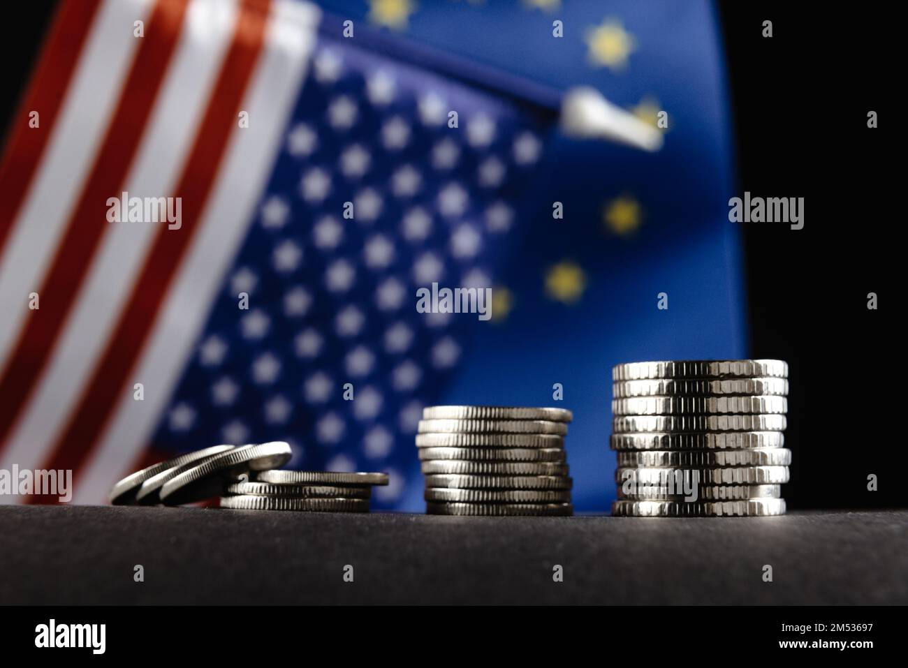 Geld der Vereinigten Staaten und Europas und Two Flags auf dunklem Hintergrund. Es ist ein Symbol der steigenden Zollsteuer in den Vereinigten Staaten von Amerika Stockfoto
