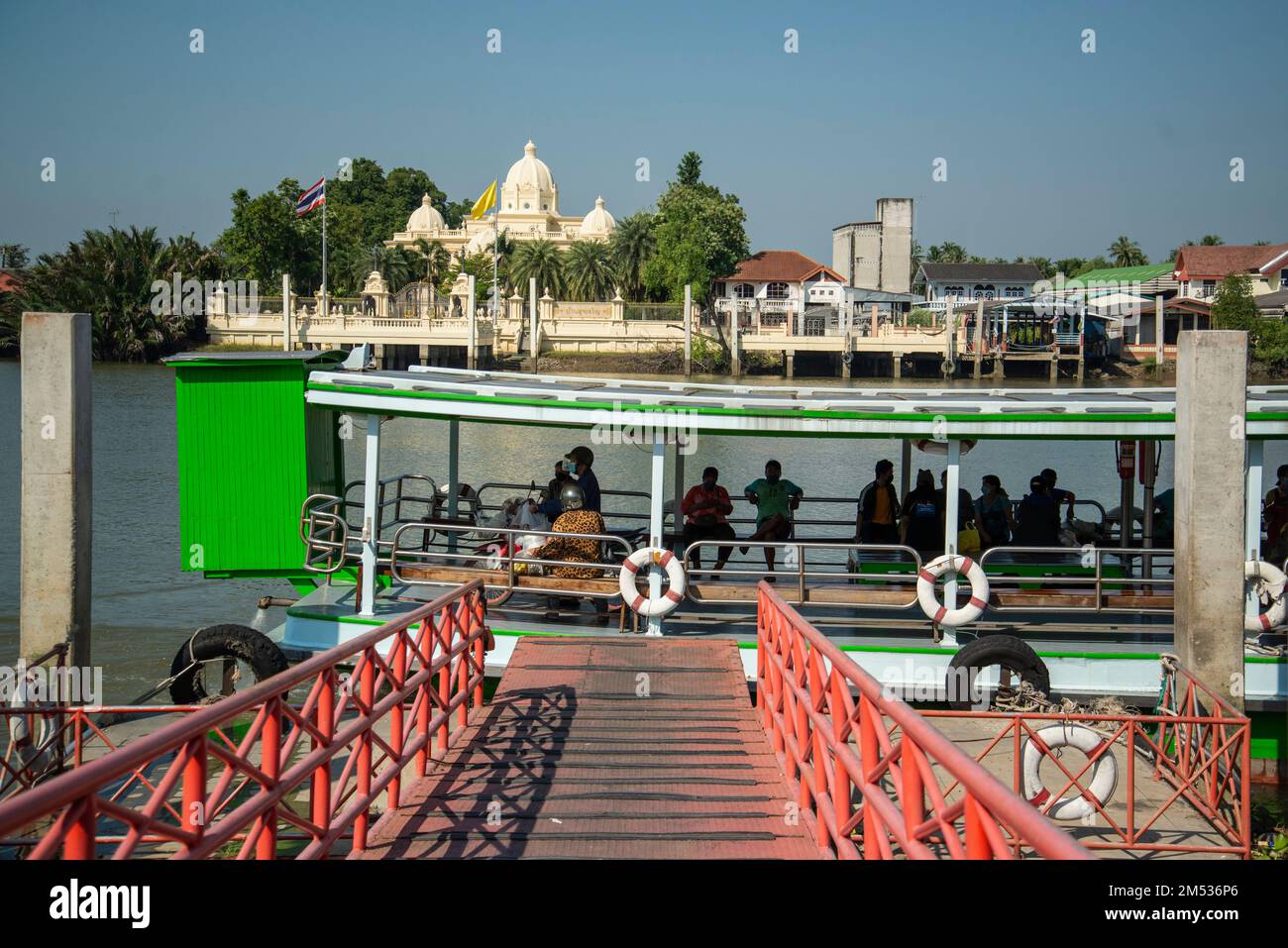 Ein Boot mit öffentlichen Verkehrsmitteln vor einem Palast am Fluss Mae Klong in der Stadt Samut Songkhram oder Mae Klong in der Provinz Samut Songkhram in Stockfoto