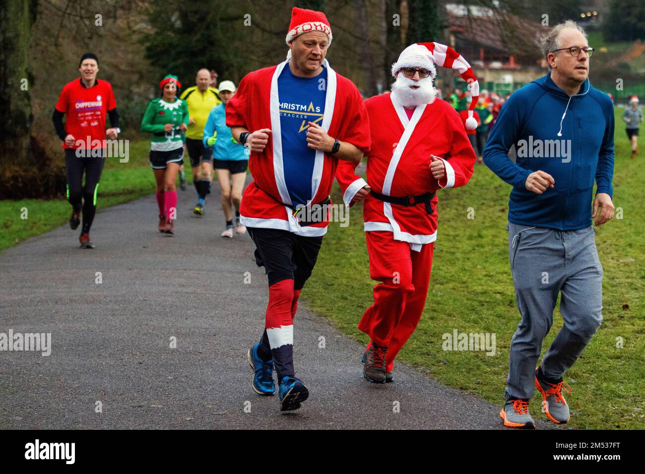 Chippenham, Wiltshire, Großbritannien. 25. Dezember 2022. Läufer in schicken Kleidern nehmen an einem 5km Park Run am frühen Weihnachtsmorgen in Monkton Park, Chippenham, Wiltshire Teil. Das feuchte Wetter hat die Stimmung der 200-300 Personen, die an der Veranstaltung teilgenommen haben, nicht geschwächt, viele von ihnen haben sich in schicken Kleidern verkleidet. Kredit: Lynchpics/Alamy Live News Stockfoto