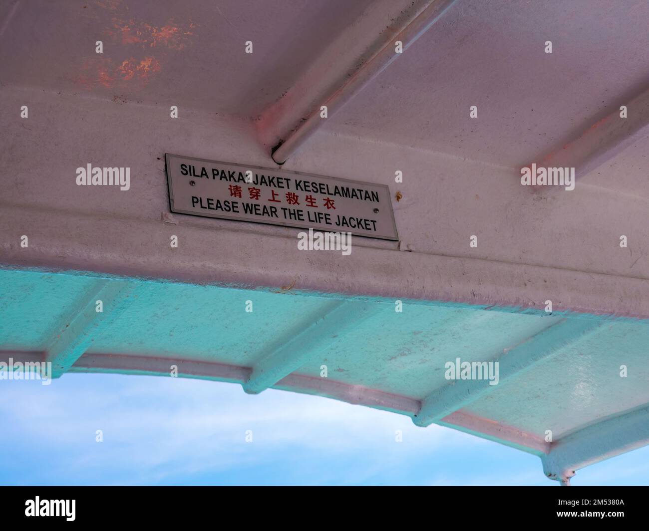 Bitte tragen Sie das Schild mit der Schwimmweste auf dem Boot in Englisch, Malaiisch und Chinesisch. Stockfoto