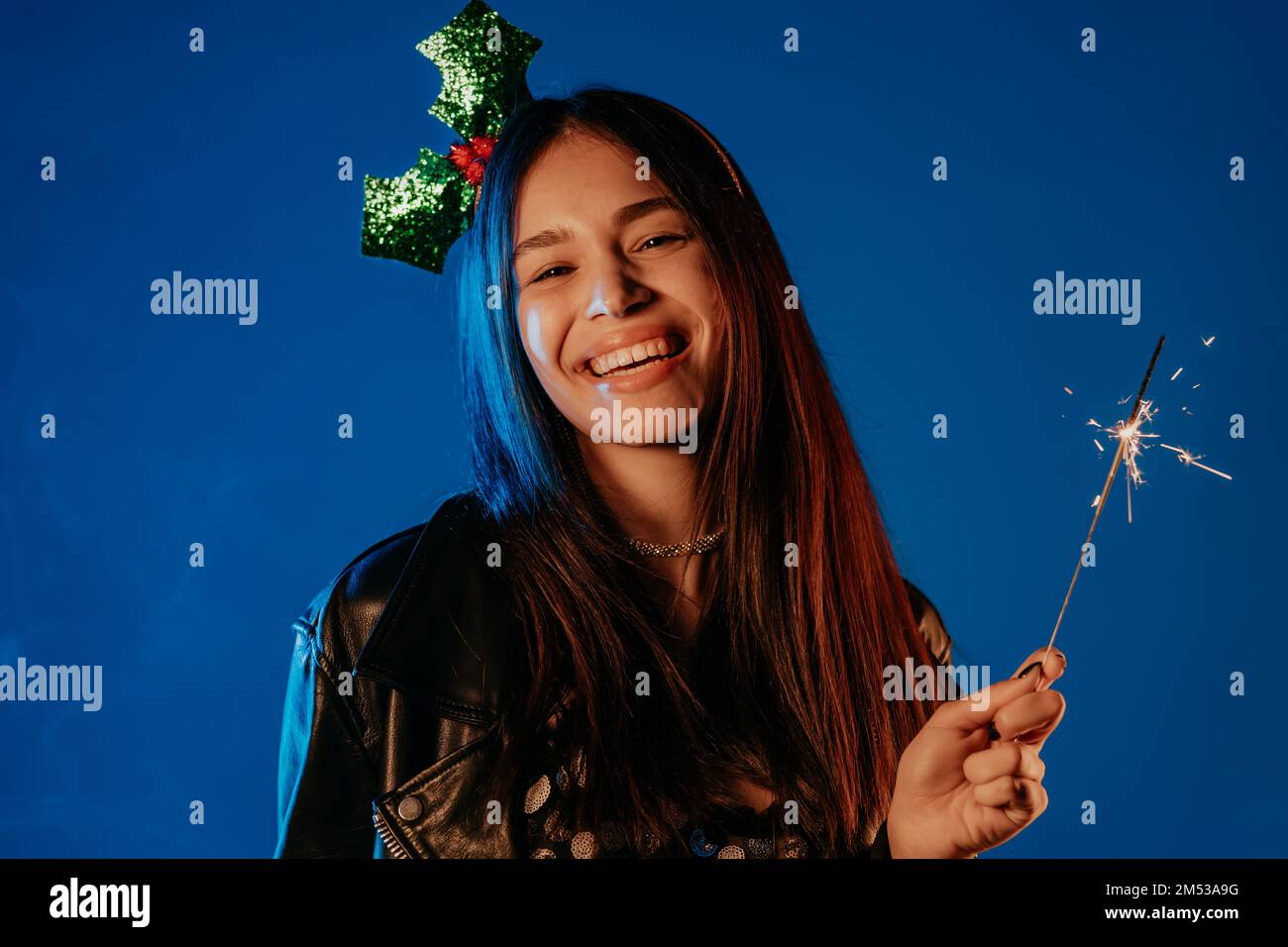 Junge asiatische Teenagerin, die mit dem bengalischen Glitzerfeuer unter Neonlicht tanzt. Neujahrsfeier oder Weihnachtsfeier. Lebendige Aufnahmen einer glücklichen Frau. Stockfoto