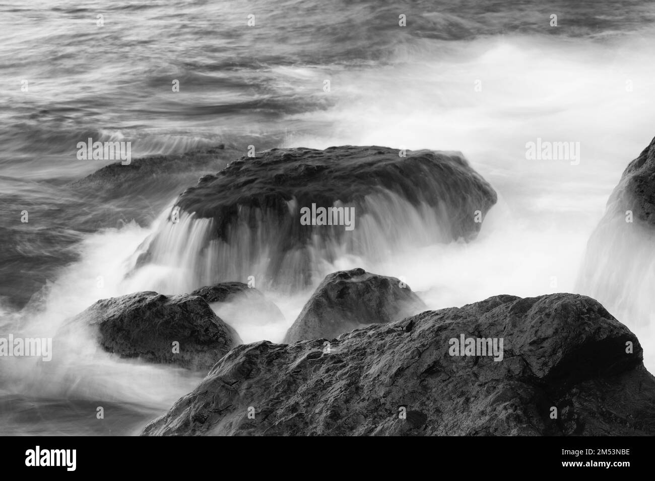 Brechende Welle am vulkanischen Kieselstrand Stockfoto