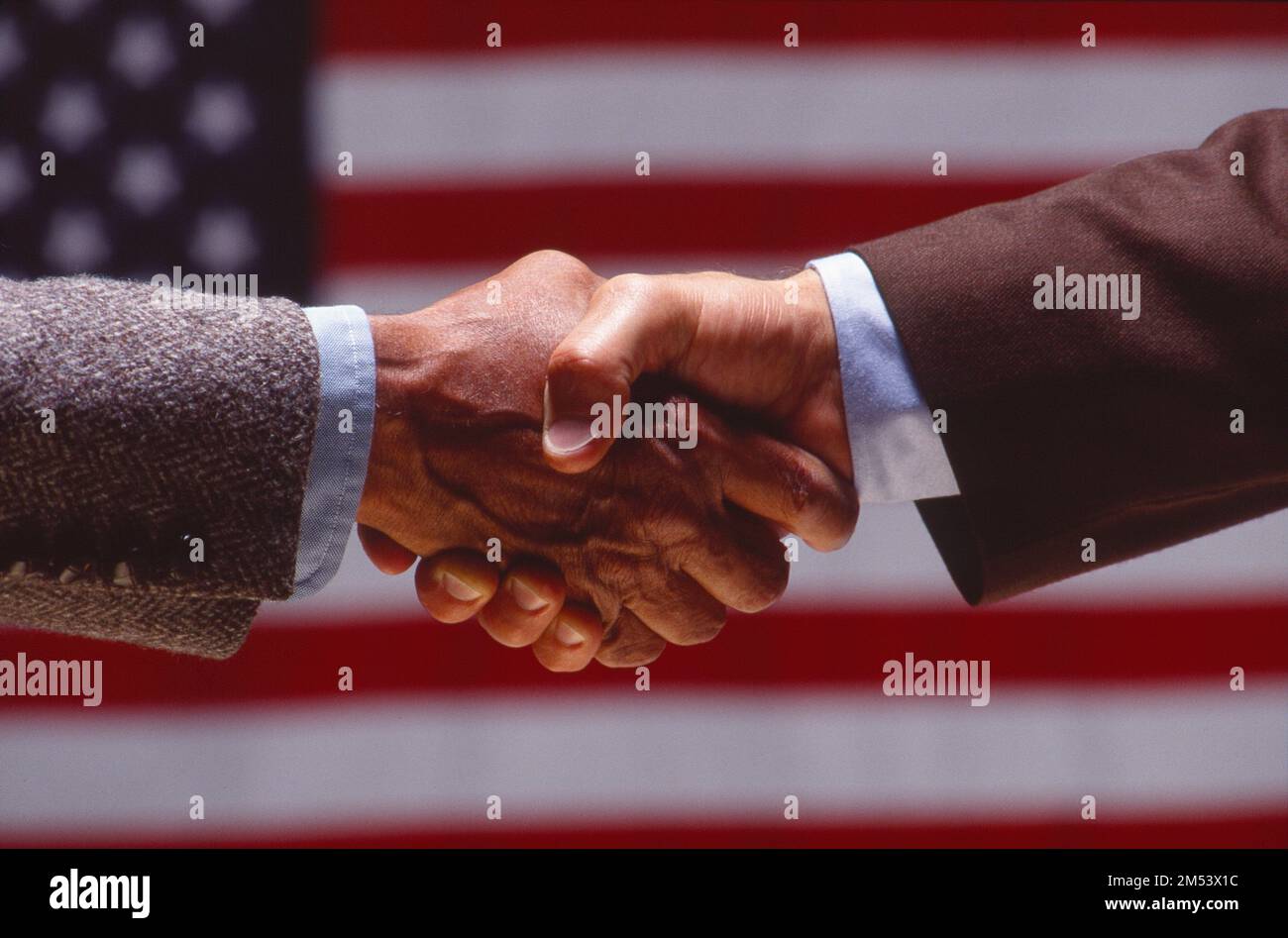 Symbolischer Schuss für Geschäftsleute, Händeschütteln mit einer amerikanischen Flagge im Hintergrund Stockfoto