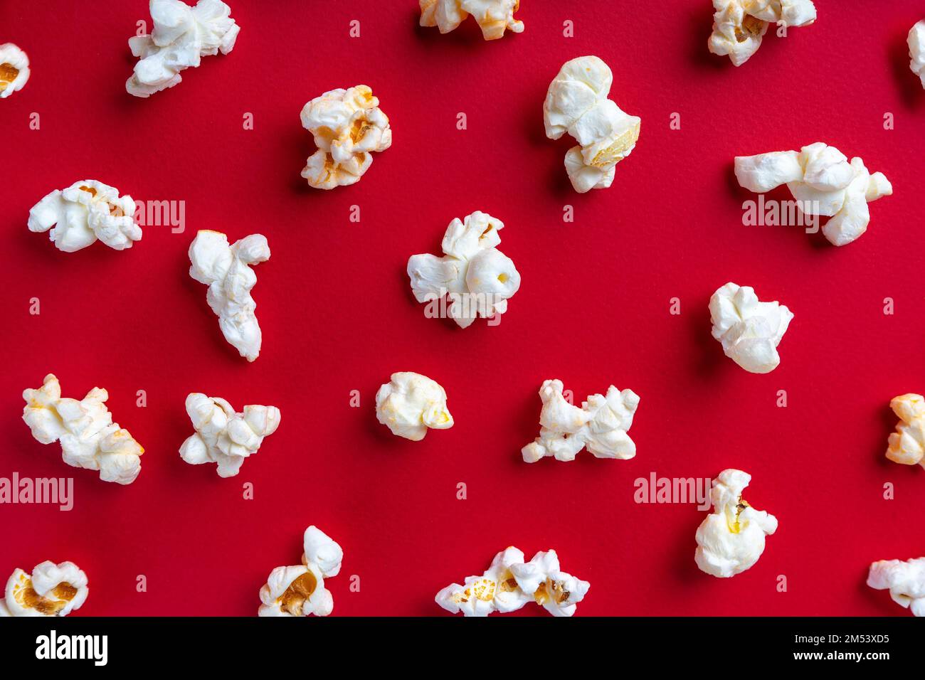 Verstreutes, leckeres Käsepopcorn, isoliert auf rotem Hintergrund. Draufsicht, flach liegend, Banner, Tapete Stockfoto