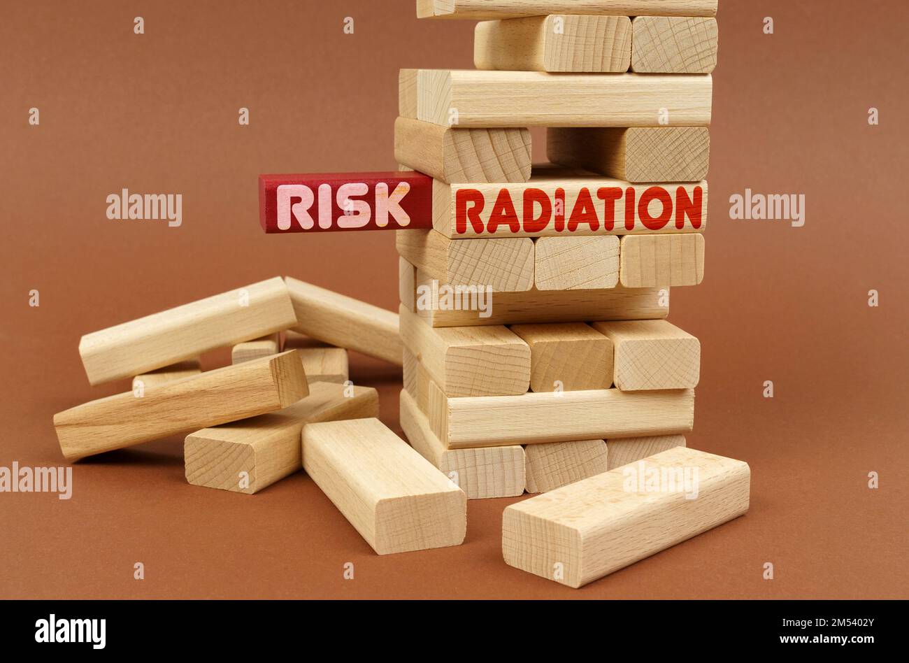Industriekonzept. Es gibt einen Holzturm auf einer braunen Oberfläche. Auf dem roten Block befindet sich die Aufschrift „Risk“ (Risiko), auf dem nächsten Block „Radiation“ (Strahlung) Stockfoto