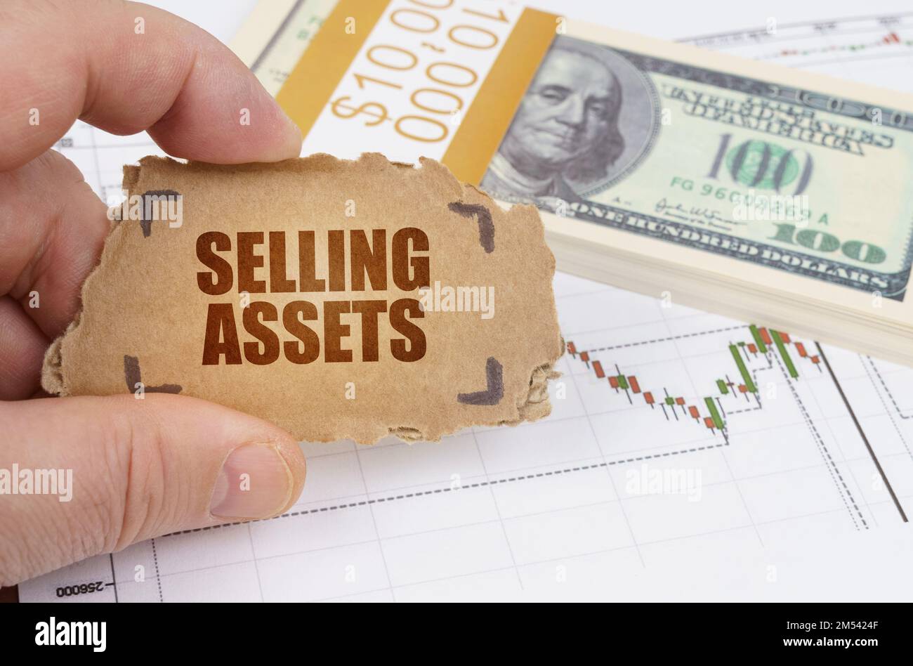 Geschäfts- und Finanzkonzept. Vor dem Hintergrund von Dollars und einer Tabelle mit Zitaten hält ein Mann ein Schild in den Händen mit der Inschrift Sell Stockfoto