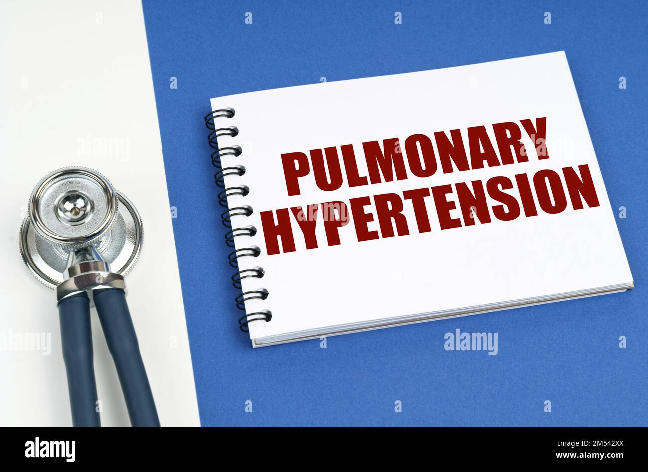 Medizinisches Konzept. Auf einer blau-weißen Oberfläche liegen ein Stethoskop und ein Notizblock mit der Aufschrift "PULMONALE HYPERTONIE" Stockfoto
