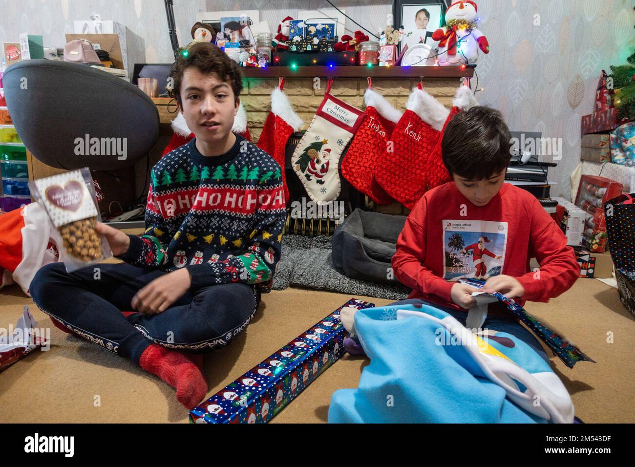 Die Brüder saßen auf dem Boden und öffneten Weihnachtsgeschenke am ersten Weihnachtsfeiertag Stockfoto
