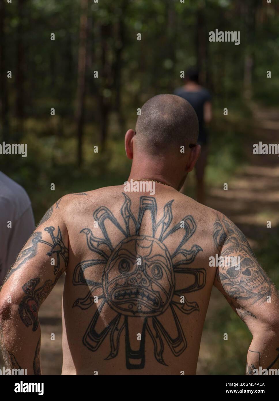 Mann mit Tattoos auf dem Rücken und den Armen, der durch einen Wald läuft, Bayern, Deutschland Stockfoto