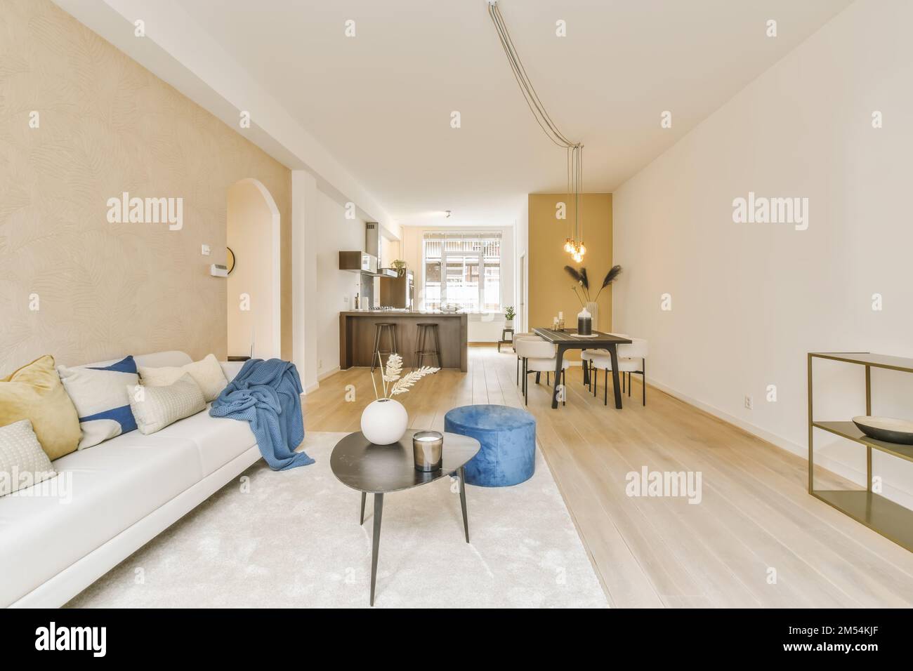 Ein Wohnzimmer mit Holzfußboden und weißen Sofas im Zimmer ist mit blauen Dekokissen dekoriert Stockfoto