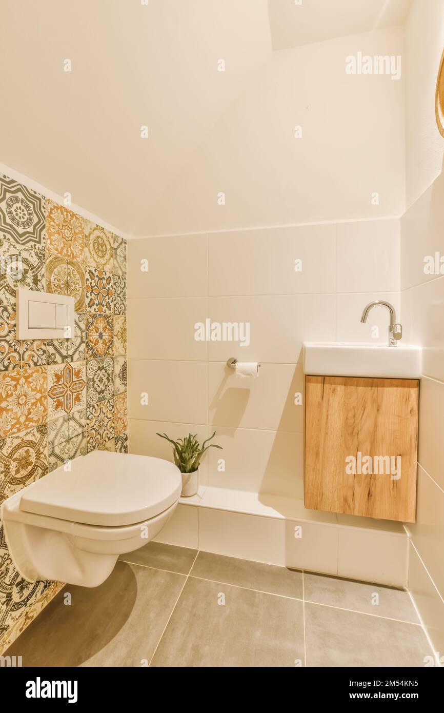 Ein Badezimmer mit künstlerischem Design auf der Tapete und die Toilette im Zimmer ist weiß, beige und orange Stockfoto