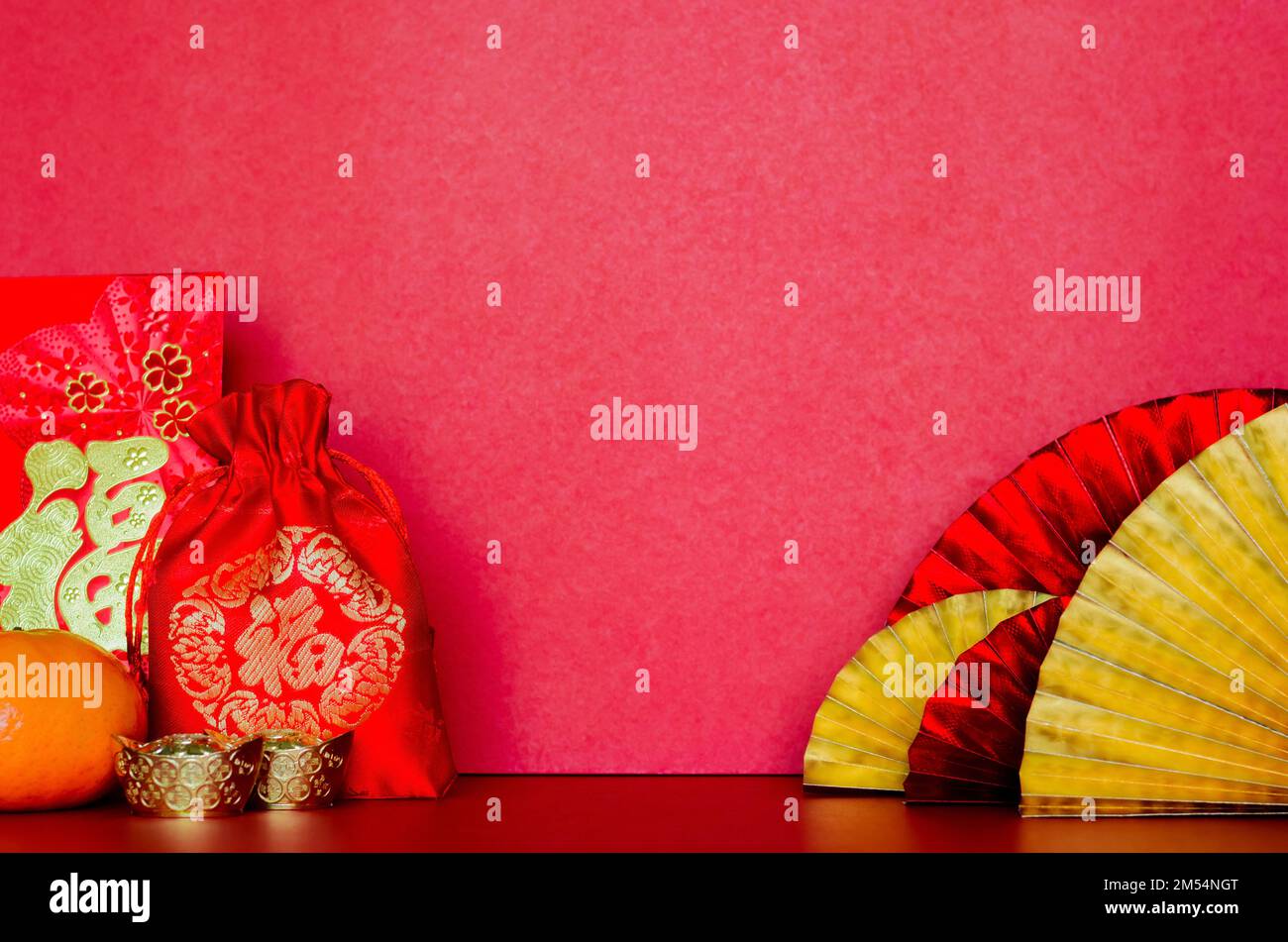 Selektiv auf rotem Beutel (Wort bedeutet Reichtum) mit Umschlagpaketen oder ang bao (Wort bedeutet Reichtum), Barren und Orange mit goldenen und roten orientalischen Fans auf r Stockfoto