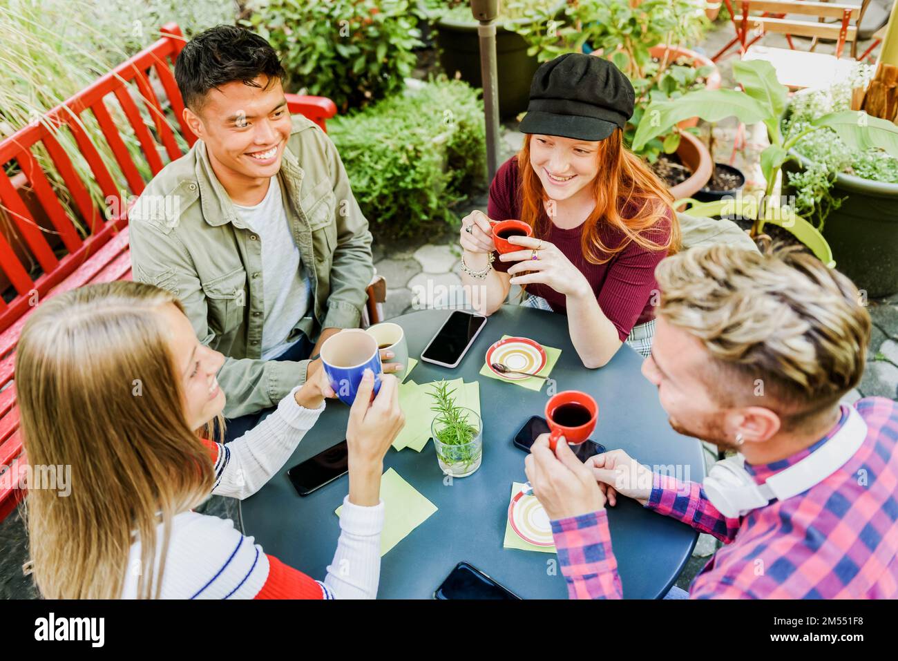 Von oben, von positiven multirassischen Freunden, die Kaffee trinken und sich anschauen, während sie auf der Terrasse des Cafés frühstücken Stockfoto