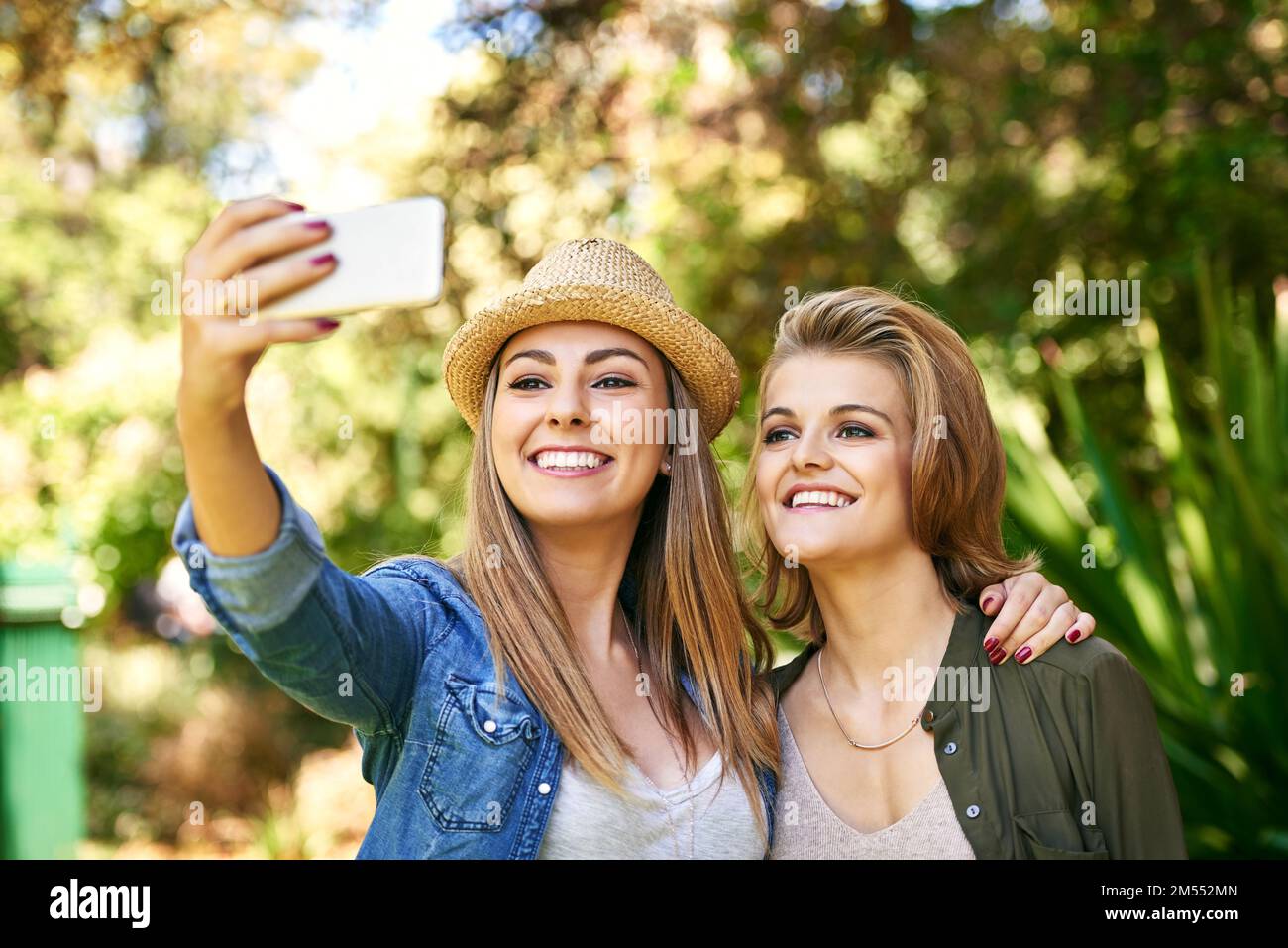 Kommen Sie noch mal rein. Zwei attraktive junge Frauen, die draußen Selfies machen. Stockfoto