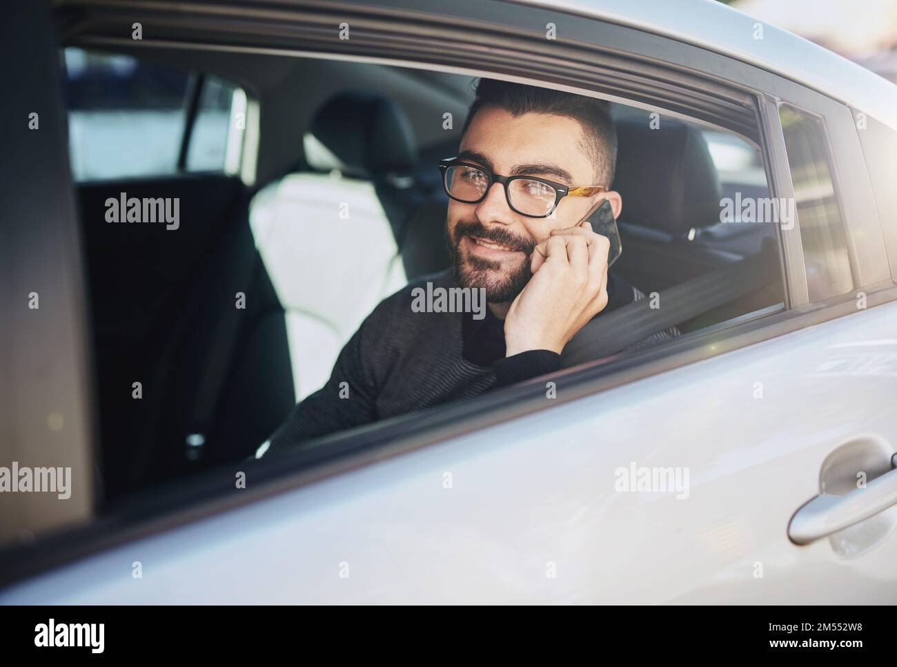 Immer unterwegs. Porträt eines jungen Mannes, der mit einem Handy im Auto spricht. Stockfoto