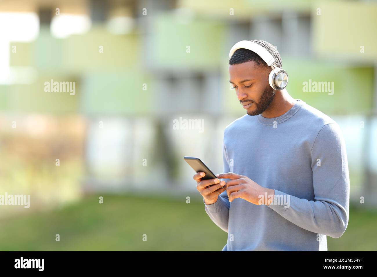 Ein Schwarzer, der auf der Straße Musik auf dem Smartphone überprüft Stockfoto