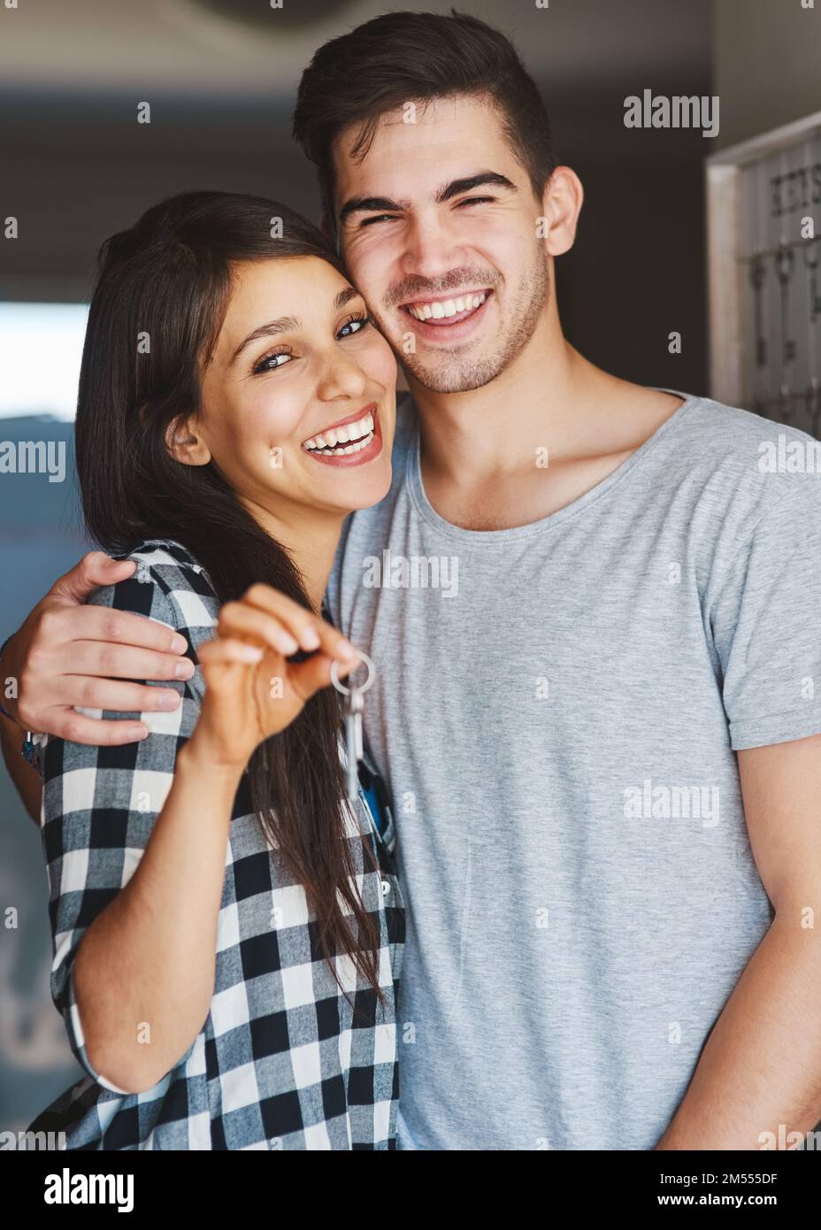 Schick dir eine Einladung zu unserer Einweihung. Porträt eines glücklichen jungen Paares, das vor der Tür seines neuen Heims steht. Stockfoto