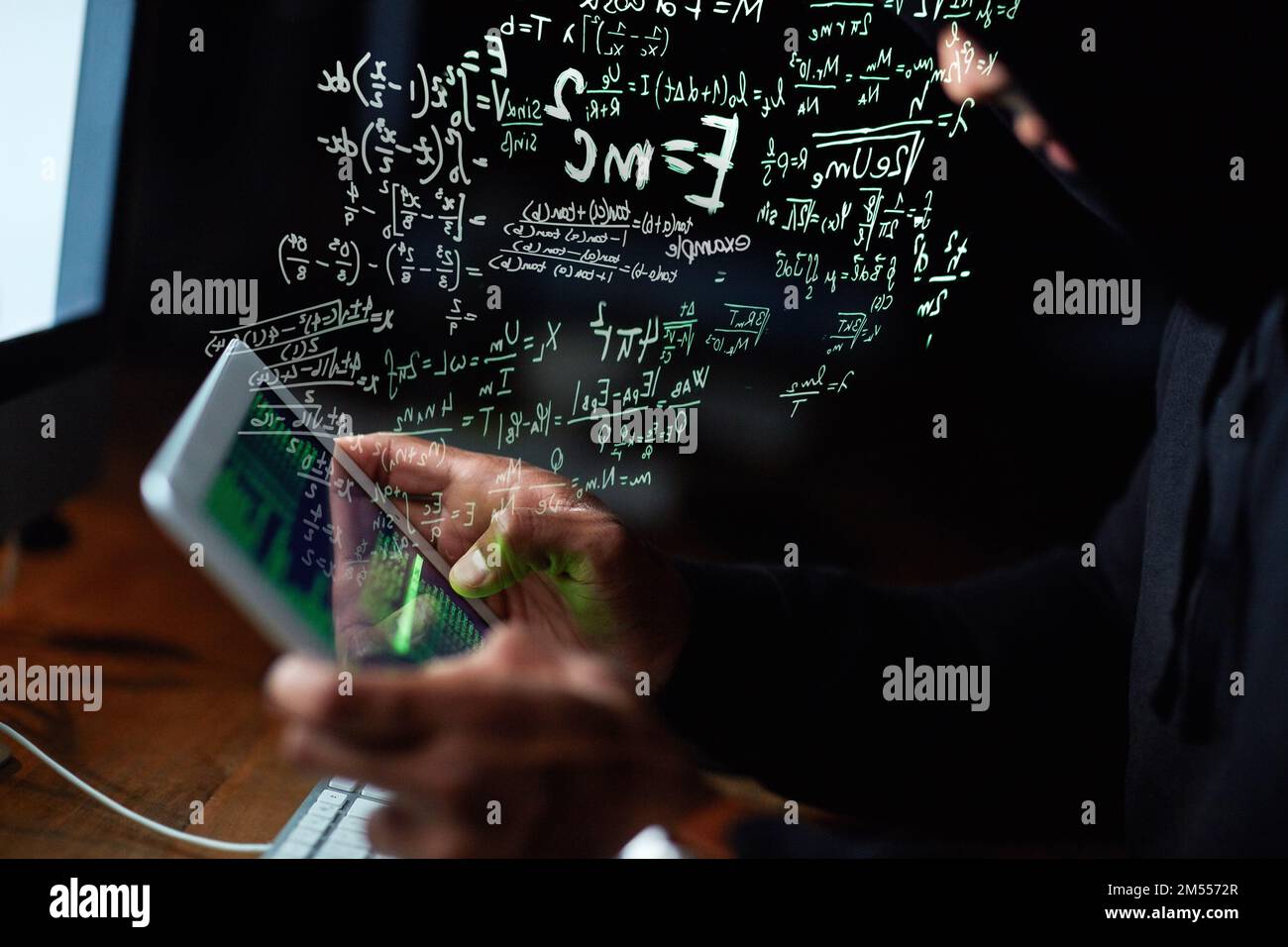 Technologisch fließend. Ein junger Hacker knackt einen Computercode im Dunkeln. Stockfoto