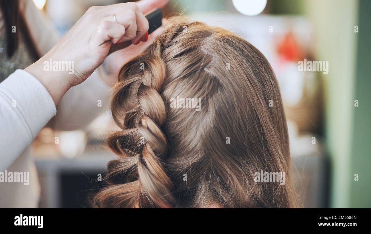 Die Make-up-Künstlerin macht einen Zopf für das Model. Stockfoto