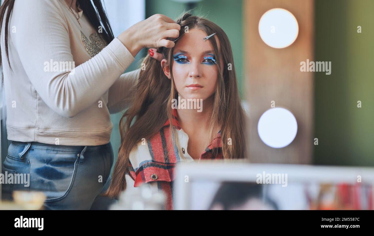 Die Make-up-Künstlerin macht einen Zopf für das Model. Stockfoto