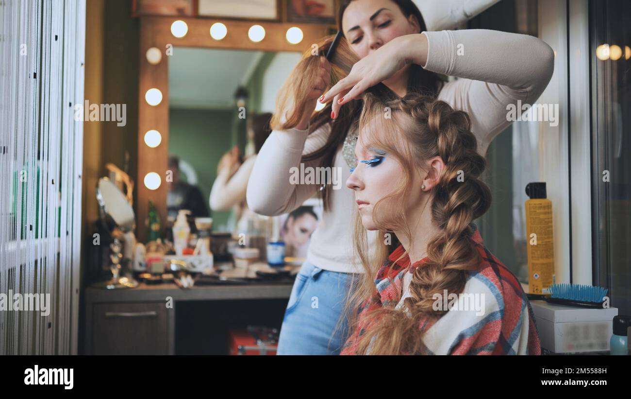Die Make-up-Künstlerin macht einen Zopf für das Model. Stockfoto