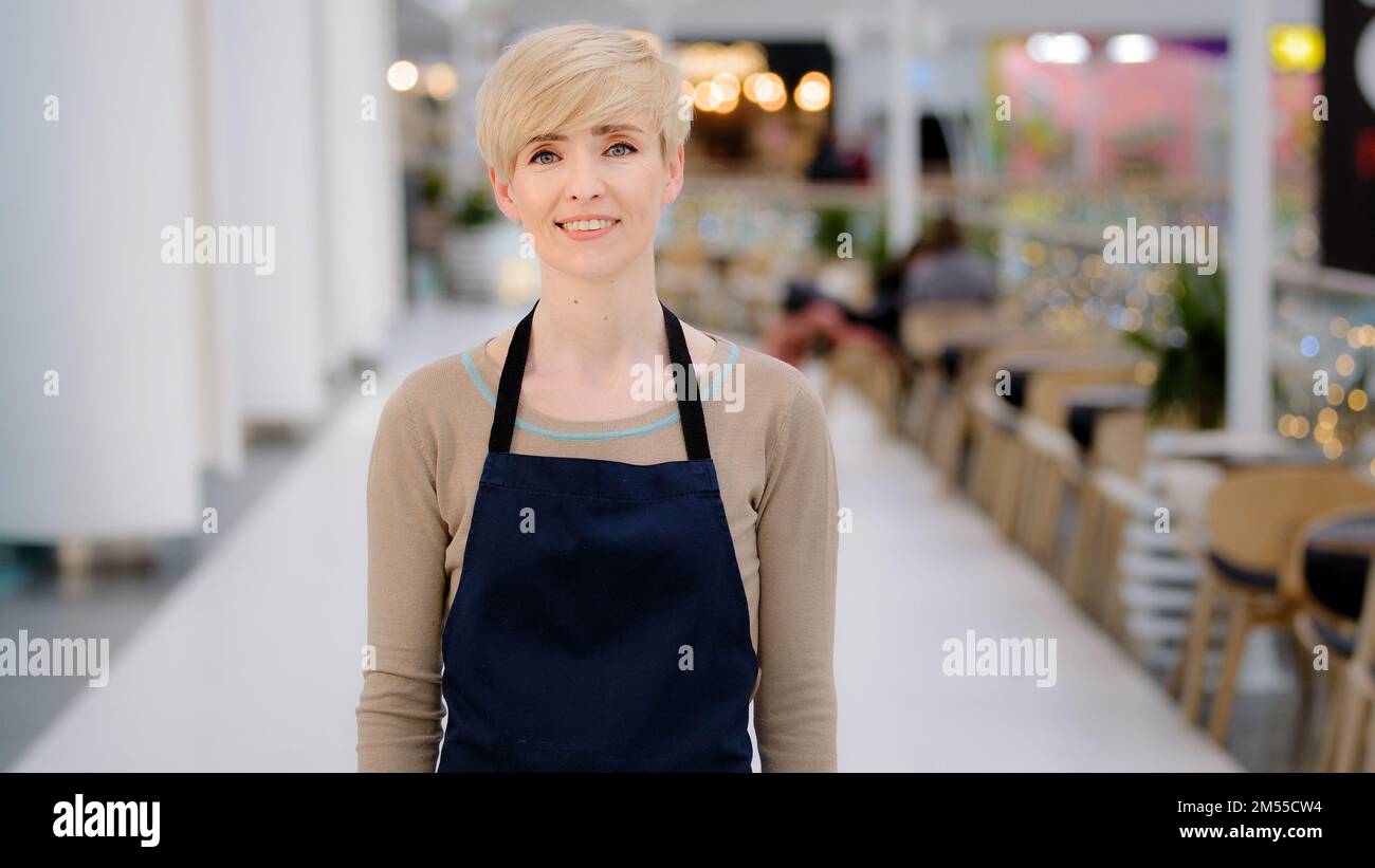Porträt weibliche Mitarbeiterin im Café. Reife, 40s-köpfige Erwachsene Frau mittleren Alters, die ziemlich lächelnde Kellnerin, Restaurantbesitzerin, Verkäuferin im Einkaufszentrum Stockfoto