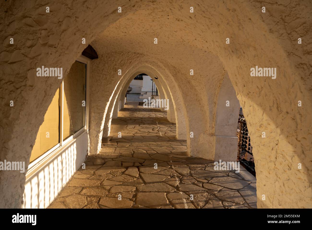 Sonnenlichtbogen mit gepflastertem Boden und Gipswänden früh am Morgen vor dem Hotelgebäude auf dem Resort Stockfoto