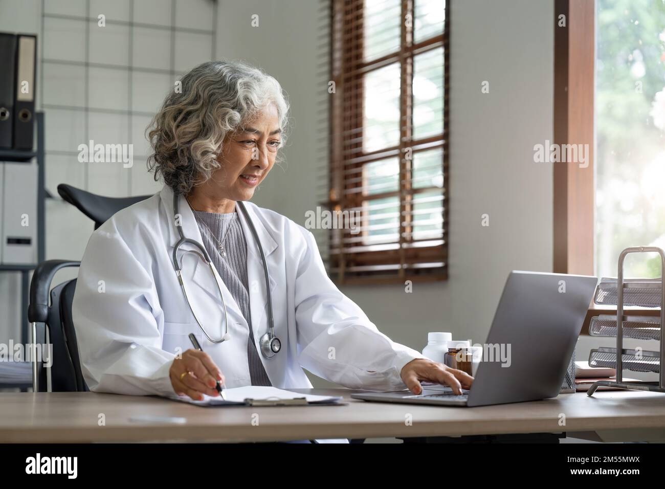 Ärztin im Laborkittel arbeitet und notiert sich Informationen über den Patienten Stockfoto