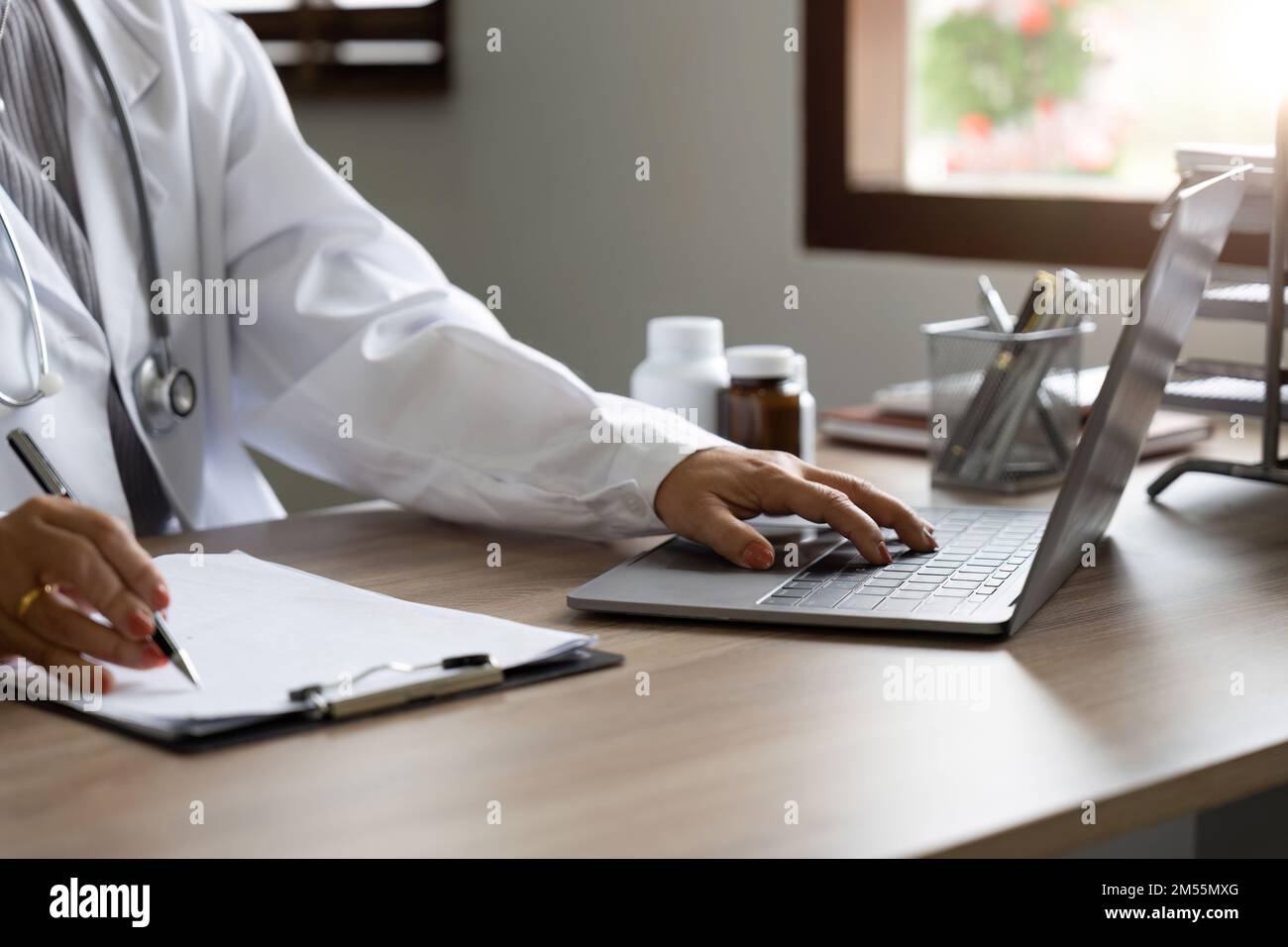 Ärztin im Laborkittel arbeitet und notiert sich Informationen über den Patienten Stockfoto