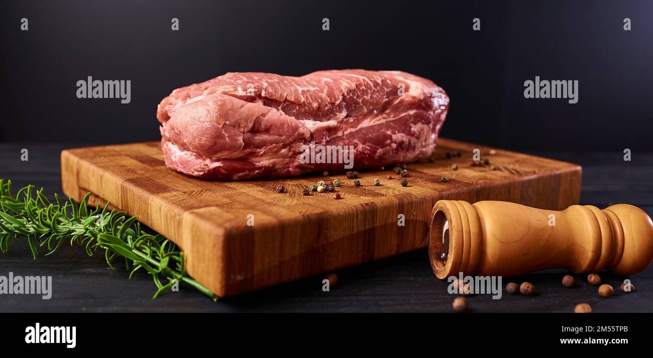 Rohes Fleisch. Rohes Rindfleischsteak auf ein Schneidebrett mit Rosmarin und Gewürzen. Stockfoto