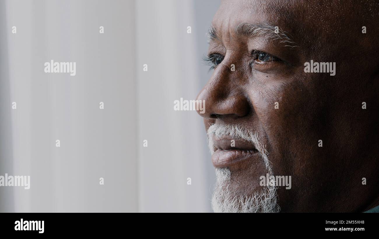 Nahaufnahme des nachdenklichen männlichen alten, zerknitterten Gesichts, 60s bärtiger afrikanischer Mann tief in traurigen Gedanken, der auf das Fenster schaut, älterer Großvater schaut weg, denk an Stockfoto