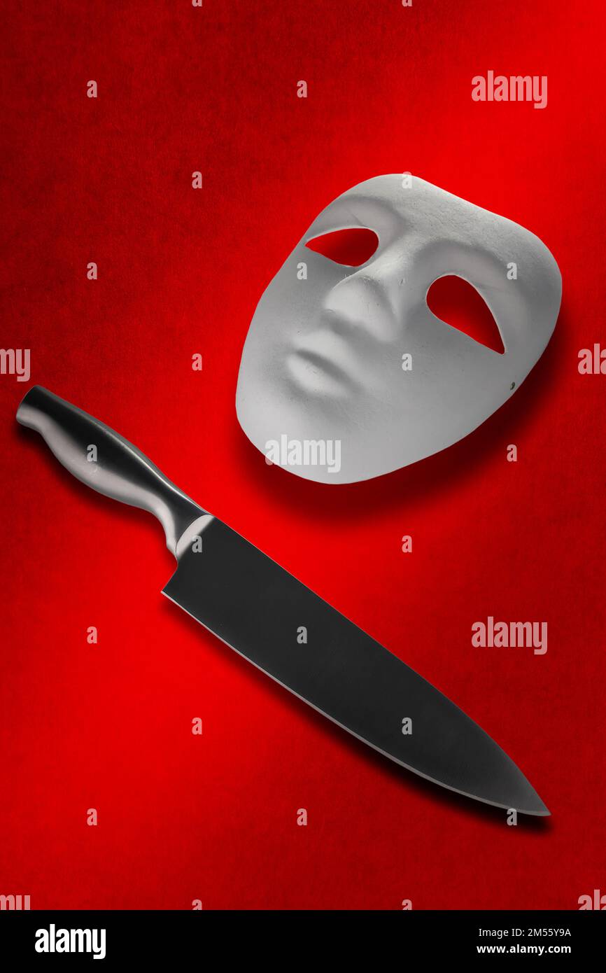Nahaufnahme einer Maske und eines Messers auf einem gebürsteten roten Hintergrund. Stockfoto