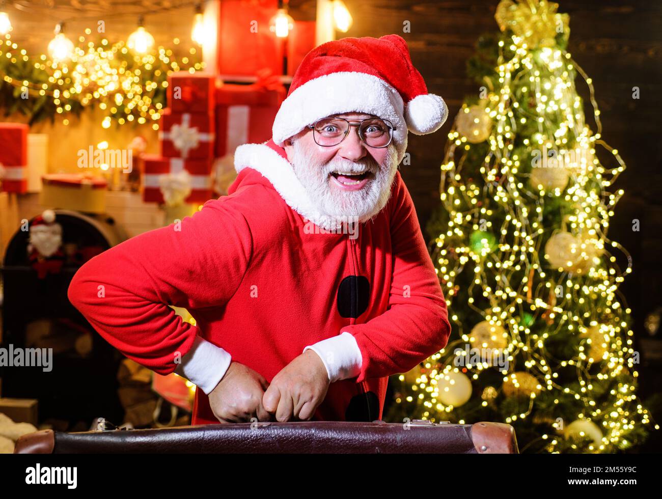 Weihnachtsfeiertage. Fröhlicher Weihnachtsmann mit Koffer. Neujahrsreisen, Touristenreisen, Urlaub. Stockfoto