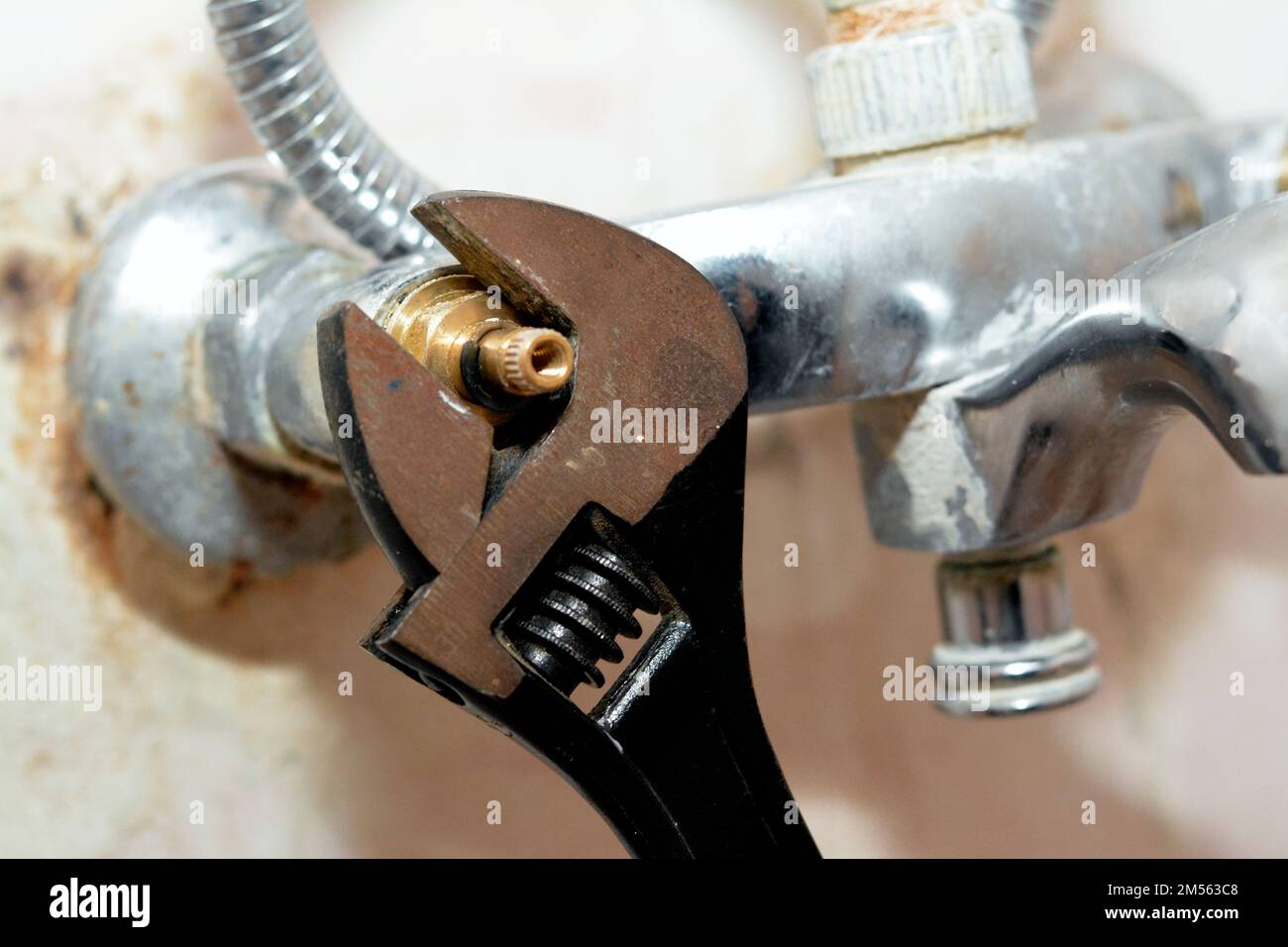 Ein Klempner, der ein Problem mit einem Wasserhahn in der Dusche löst, der den Kartuschenkörper mit einem verstellbaren Schraubenschlüssel dreht, um ihn, die Leitungen und die Wartungskosten zu wechseln Stockfoto