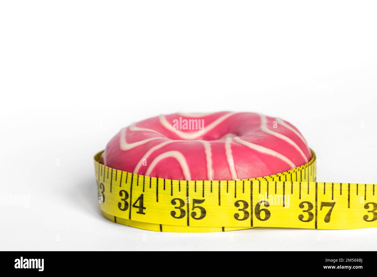 Rosa Donut und Meter, das Konzept der Gewichtszunahme und Gewichtsabnahme. Stockfoto